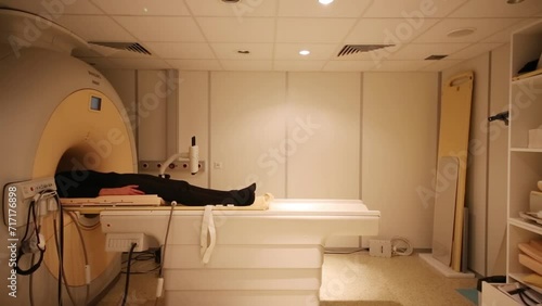 The patient lies on MRI scanner bed in the room  photo