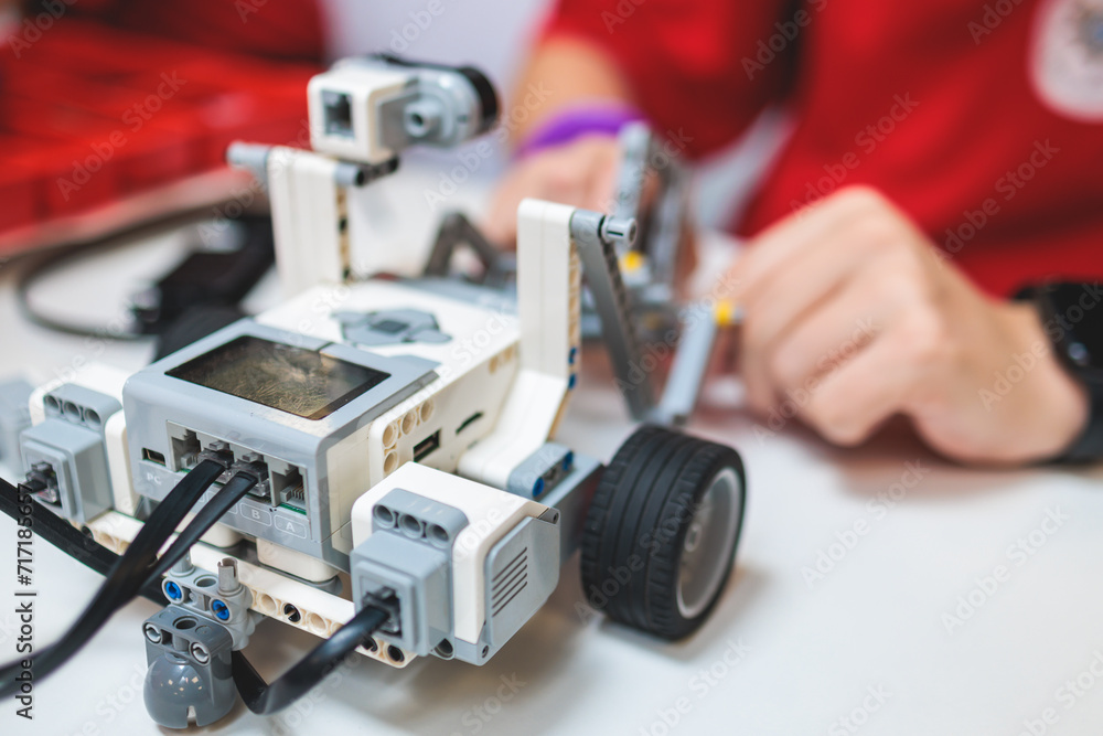 Group of diverse children kids with robotic vehicle model, close-up view on hands, science and engineering lesson in a classroom, making, coding and programming a robot in a school, robotics projects Group of diverse children kids with robotic vehicle model, close-up view on hands, science and engineering lesson in a classroom, making, coding and programming a robot in a school, robotics projects