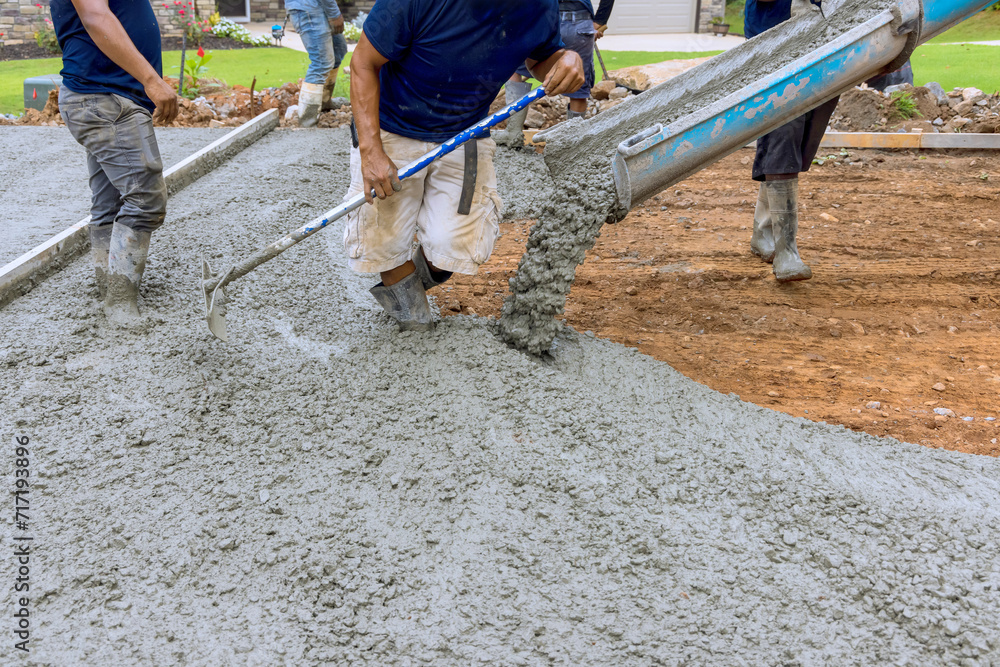 Using concrete mixing truck workers poured wet cement onto driveway of new house Using concrete mixing truck workers poured wet cement onto driveway of new house