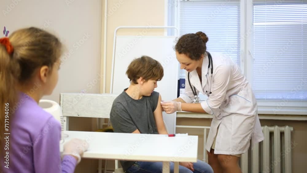 children sit in room and doctor prepares arm of boy for injection children sit in room and doctor prepares arm of boy for injection
