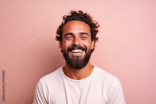 Portrait of a handsome young man with curly hair smiling against pink background photo
