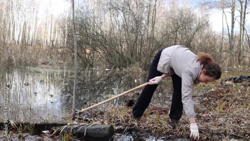 Woman pulls out garbage from water during cleaning of territory photo