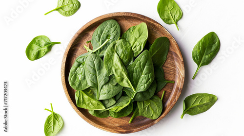 wooden round plate with fresh spinach leaves, top view photo