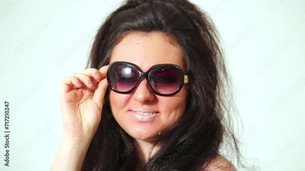 Dark-haired laughing girl model in dark sunglasses poses at studio. Dark-haired laughing girl model in dark sunglasses poses at studio.