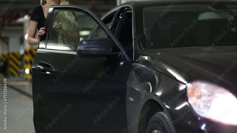 Beautiful blonde woman opens and closes door of black car Beautiful blonde woman opens and closes door of black car