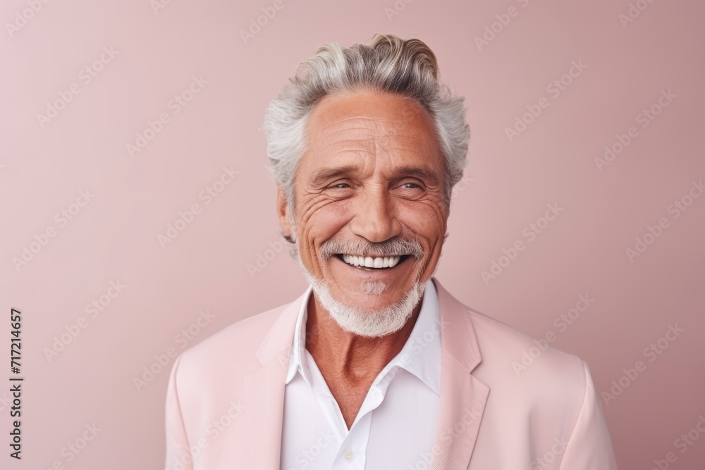 Handsome senior man smiling at camera while standing against pink background Handsome senior man smiling at camera while standing against pink background