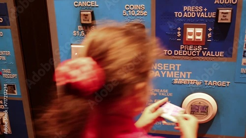 Little girl is paying for a farecard in the subway. photo