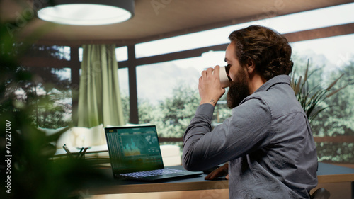 Foto Rich investor hopping online on laptop to help his employees from his expensive opulent villa in the mountains
