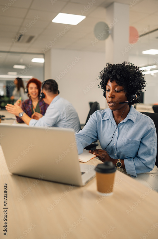 Fototapeta premium African american female agent wearing headset and resolving problems remotely