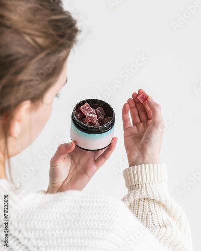 Woman holding CBD gummy in hand to take