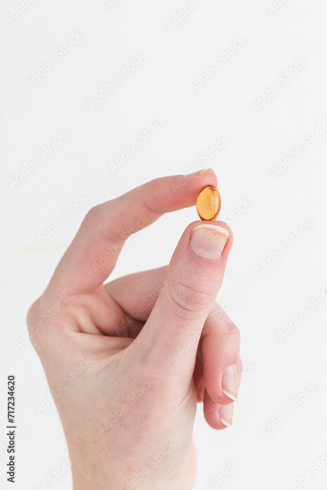 Woman holding and taking yellow vitamin pill in hand Woman holding and taking yellow vitamin pill in hand
