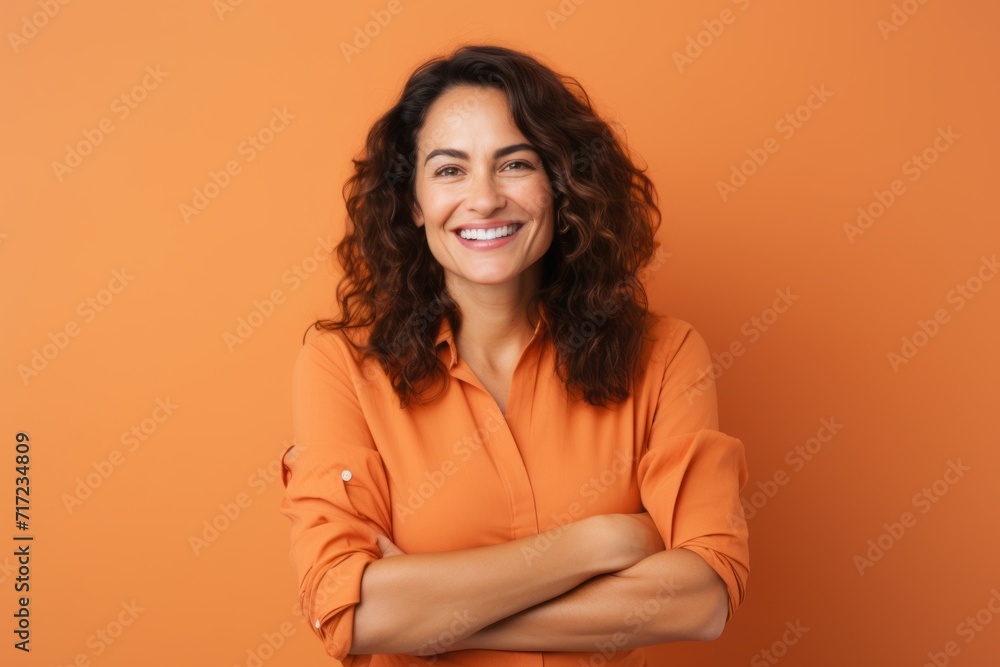 Portrait of smiling young woman with crossed arms isolated over orange background Portrait of smiling young woman with crossed arms isolated over orange background