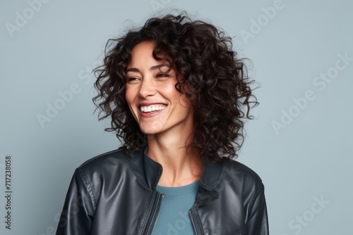 Portrait of a beautiful young woman with curly hair laughing against blue background