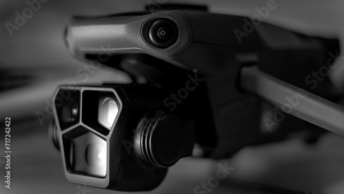 Black and white macro image of a drone from front right side. 3 camera gimbal in sharp focus with body in bokeh.