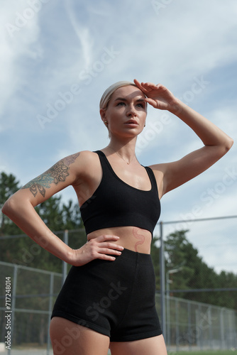 Athletic woman ready for workout, gazing into the distance on a sunny day at the sports court