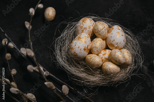 golden and white eggs in the nest beside the wilow on black rustic background. easter background photo