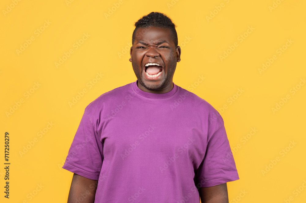 Portrait of angry african man in purple t-shirt shouting loudly Portrait of angry african man in purple t-shirt shouting loudly