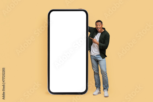 Excited young black man posing by phone with white screen