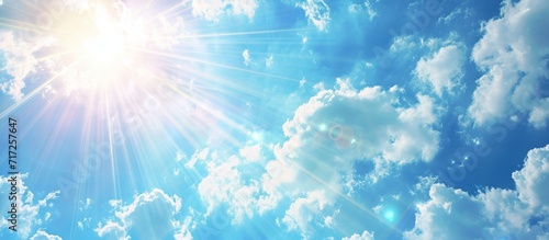 Abstract background with light flare from the sun, featuring a summer blue sky and white clouds.