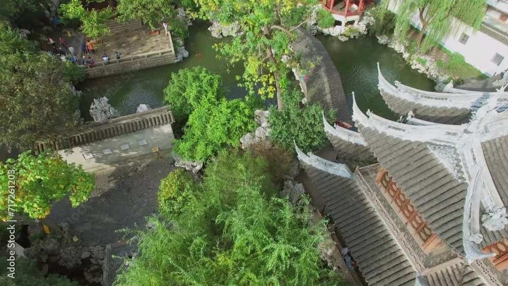 Tourists walk near pond and ancient style buildings in Yuyuan Garden Tourists walk near pond and ancient style buildings in Yuyuan Garden