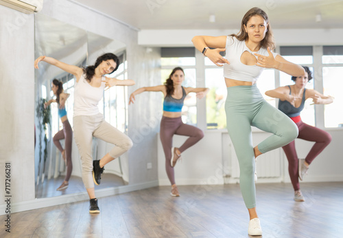 Enthusiastic young girl honing hip-hop moves in dance studio setting with group of women..