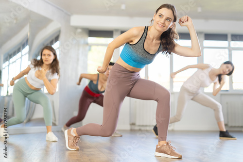 Enthusiastic young girl honing hip-hop moves in dance studio setting with group of women..