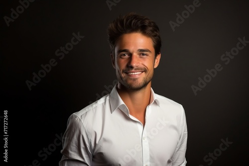 Portrait of a handsome young man in white shirt on dark background