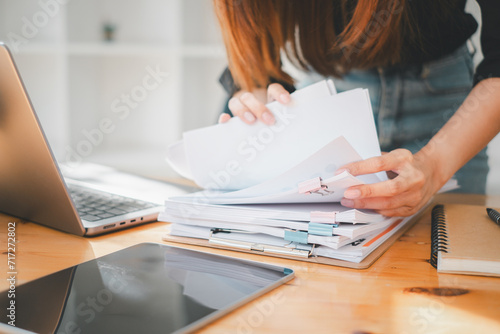 Businesswoman working in Stacks of paper files for searching and checking unfinished document achieves on folders papers at busy work desk office.