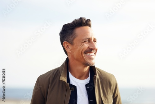 Portrait of a handsome young man standing on the beach and laughing