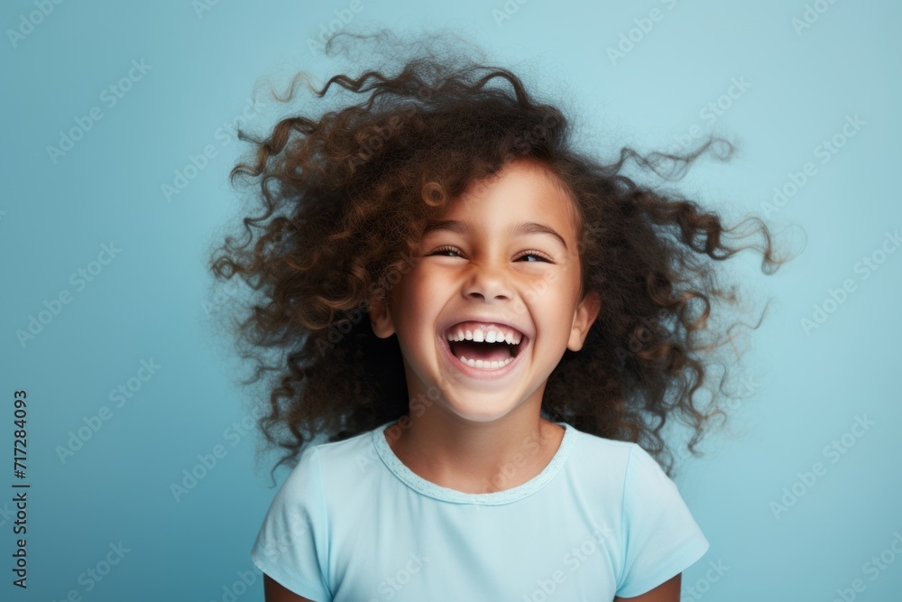 Portrait of a happy little girl with curly hair on a blue background