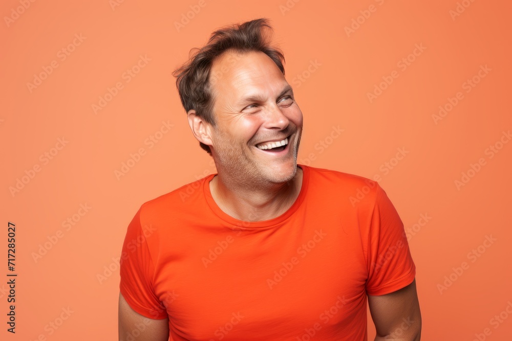 Portrait of a laughing man in orange t-shirt on orange background Portrait of a laughing man in orange t-shirt on orange background