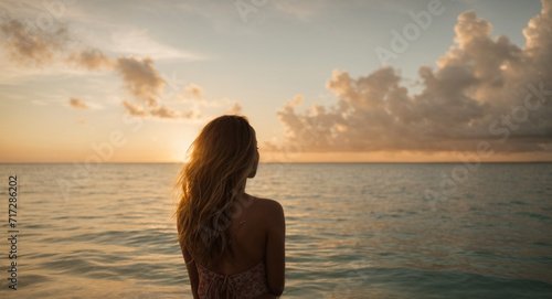 Rear view shot from behind of a young woman spending time meditating in the sea at sunset  © anandart