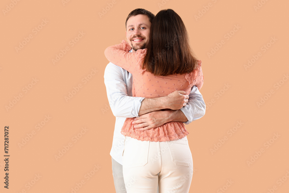 Happy young couple hugging on beige background Happy young couple hugging on beige background
