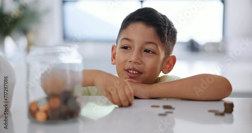 Education, boy and savings with coins in home, counting and learning of money for child development. Young kid, happy or finance lesson by jar or budget in cash investment on kitchen counter in house photo