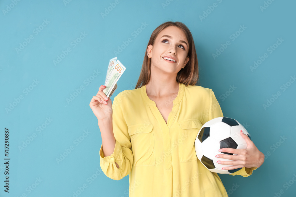 Young woman with soccer ball and money on blue background. Sports bet concept Young woman with soccer ball and money on blue background. Sports bet concept