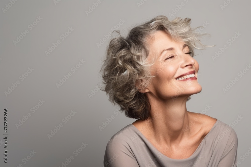 Portrait of a happy senior woman with wavy hair over grey background Portrait of a happy senior woman with wavy hair over grey background