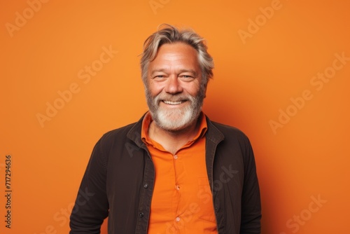 Smiling senior man with long gray hair. Studio shot on orange background. © Igor