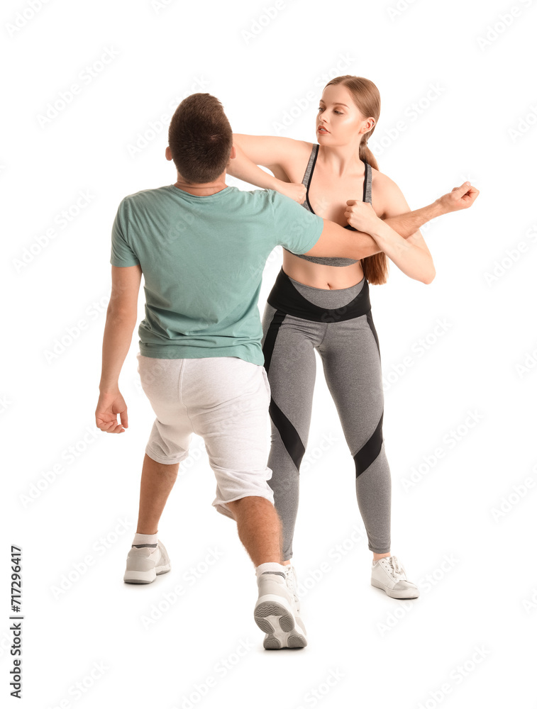 Young woman fighting with instructor of self-defence course on white background Young woman fighting with instructor of self-defence course on white background