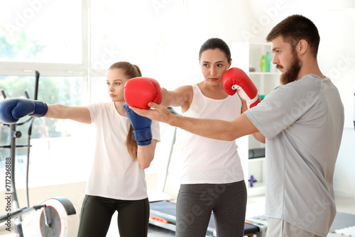 Instructor teaching young women to fight in gym. Concept of self defense photo