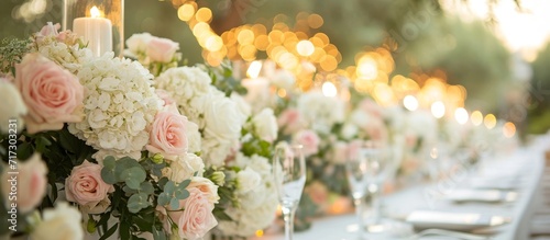 The wedding banquet in the olive grove corner table is adorned with roses and hydrangeas, creating a light and elegant ambiance in white and pink hues. photo