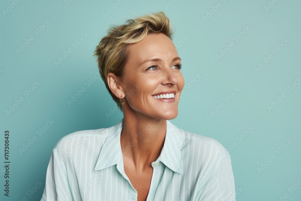 Portrait of a smiling middle aged woman looking away over blue background Portrait of a smiling middle aged woman looking away over blue background
