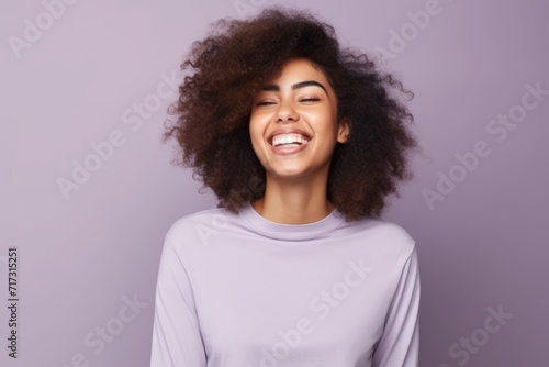 Young african american woman with curly hair on violet background.