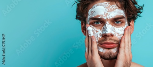 Male applying skincare product in bathroom for antiaging and wellness, with a blue studio background.