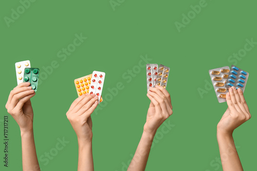 Female hands holding pills in blister packs on green background photo