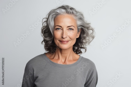 Portrait of happy mature woman with grey hair, isolated on grey background