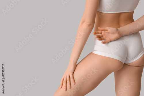 Beautiful young woman with cellulite problem on grey background, back view