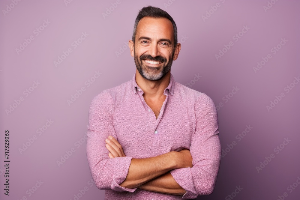 Portrait of a smiling middle-aged man with crossed arms standing against purple background Portrait of a smiling middle-aged man with crossed arms standing against purple background