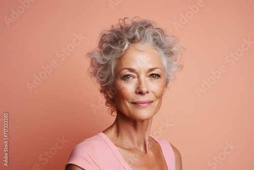 Portrait of a beautiful senior woman with gray hair on a pink background