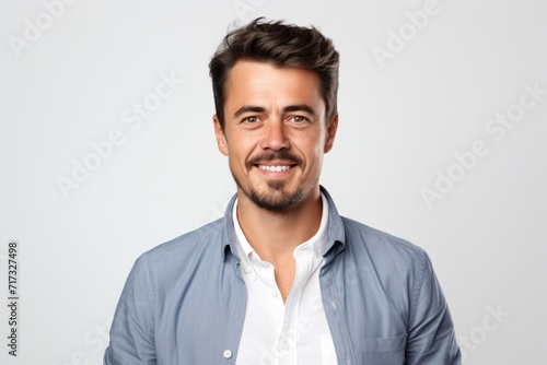 Portrait of a handsome young man smiling and looking at camera over grey background © Iigo
