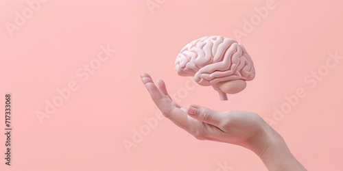 hand holding a 3D brain over a pink background photo